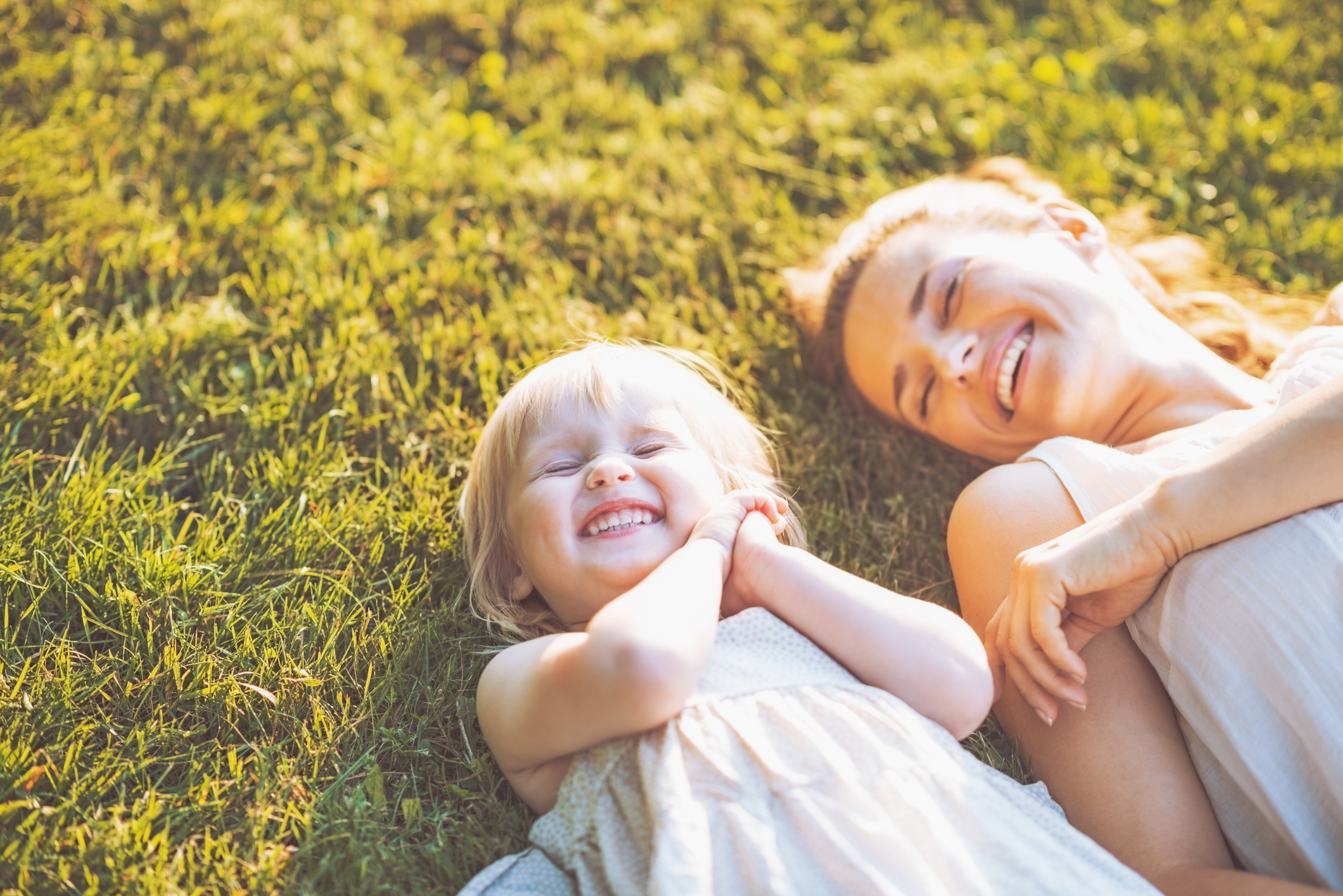 Smiling Mother and Baby Laying in Meadow